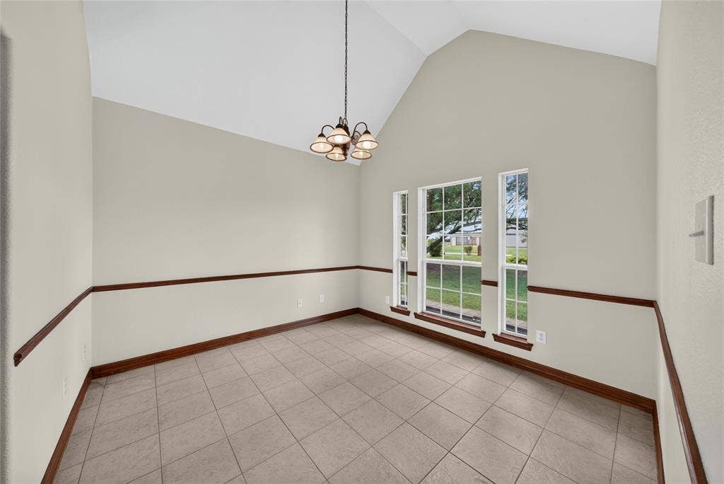 18723 Sims Lane, Nevada, TX 75173 Vaulted ceiling room featuring tiled flooring, decorative chair rail molding, and three large windows with grid patterns