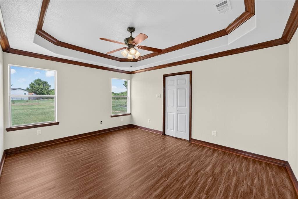 18723 Sims Lane, Nevada, TX 75173 Spacious room featuring wood-finish flooring, light-toned walls, and a tray ceiling with decorative wood trim