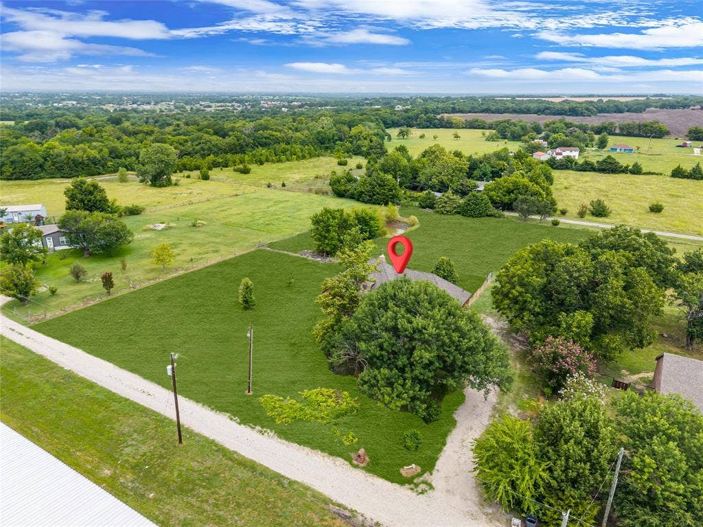 18723 Sims Lane, Nevada, TX 75173 Expansive property featuring a gravel driveway, mature trees, green lawns, and a surrounding rural landscape