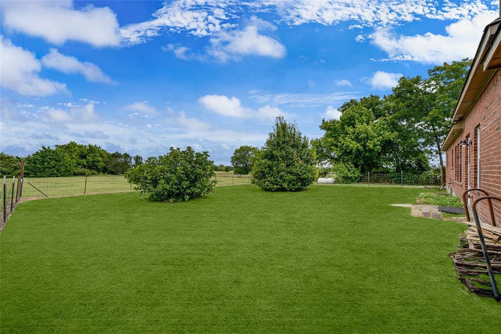 18723 Sims Lane, Nevada, TX 75173 Expansive green lawn with mature landscaping and a partial brick exterior