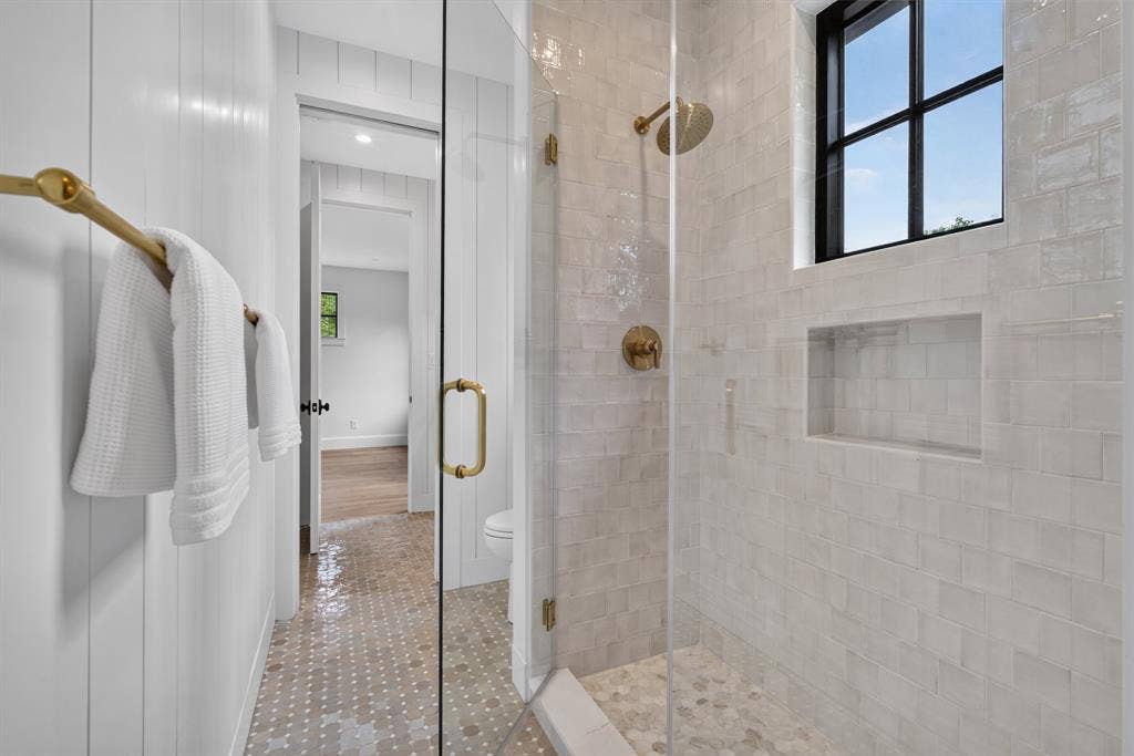 6817 Blessing Drive, Dallas, TX 75214 Spacious walk-in shower with clear glass enclosure and brass hardware