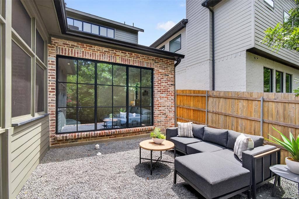 6817 Blessing Drive, Dallas, TX 75214 Private outdoor patio featuring a gravel surface, a brick facade, and a large black-framed picture window