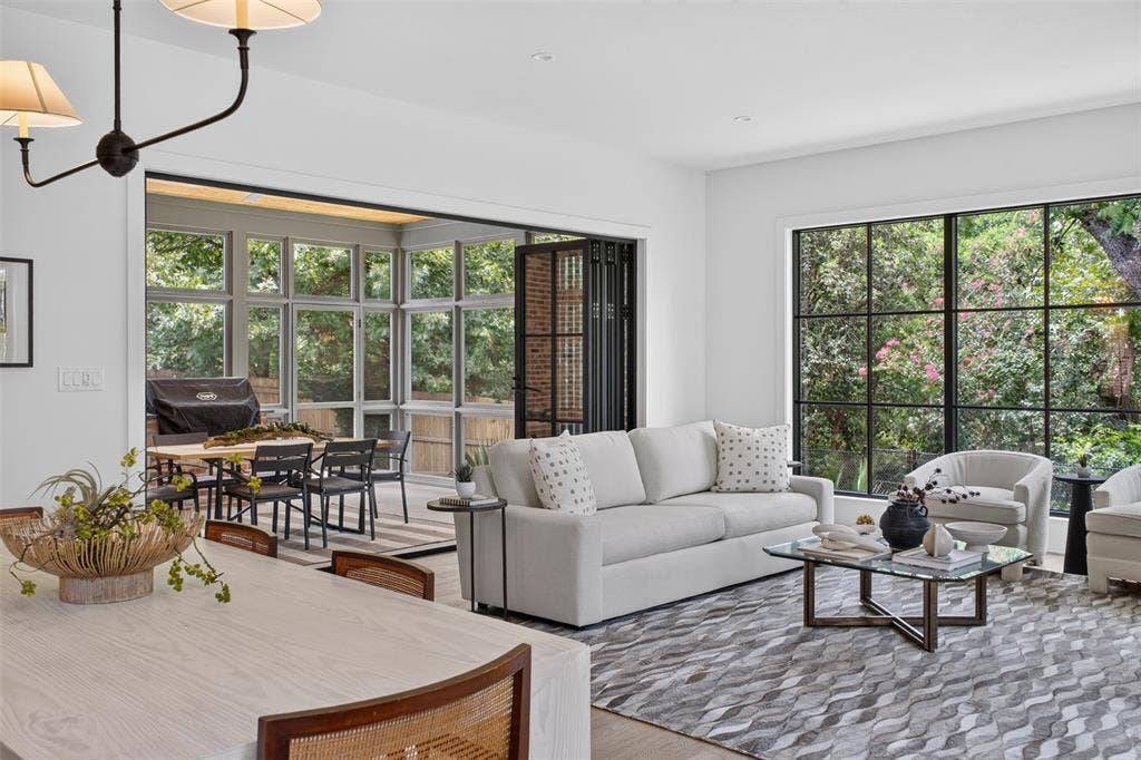 6817 Blessing Drive, Dallas, TX 75214 Bright living area featuring expansive grid-pattern windows, a retractable glass wall, wood-finish flooring, and a contemporary chandelier