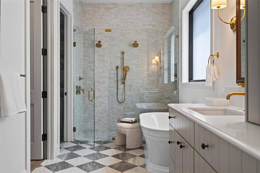 6817 Blessing Drive, Dallas, TX 75214 Bathroom featuring a glass-enclosed shower with gold-tone fixtures, a freestanding soaking tub, a single vanity with an integrated sink and gold-tone faucet, and checkerboard floor tiling