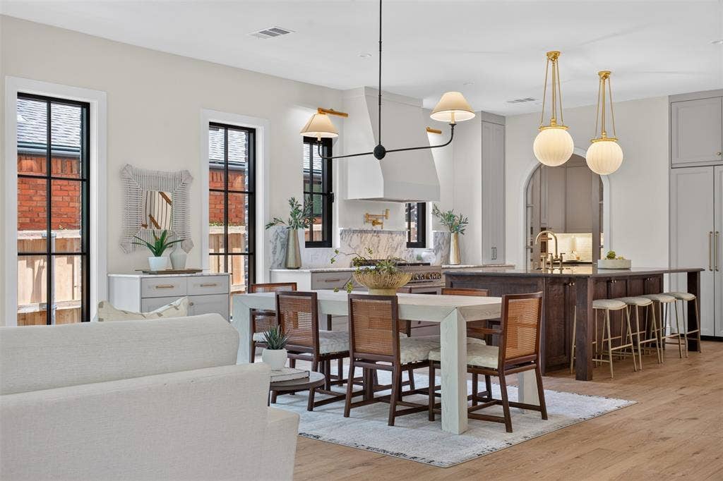 6817 Blessing Drive, Dallas, TX 75214 Open-concept living space featuring wood-finish flooring, a kitchen island with seating, a built-in range hood, and multiple windows with black framing