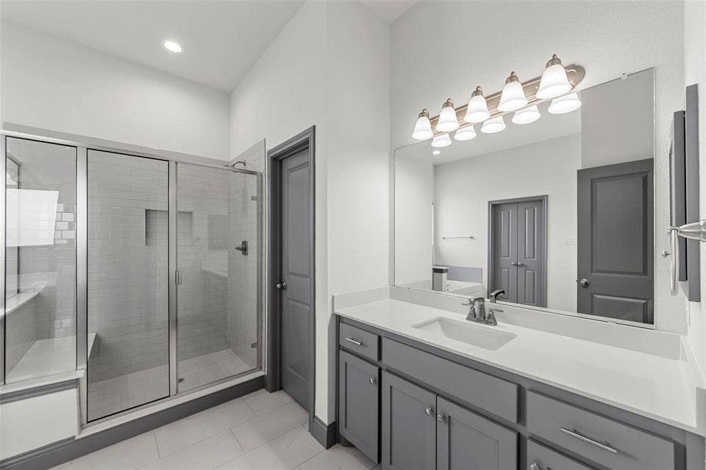 Spacious bathroom featuring a glass-enclosed shower with subway tile, built-in shower bench, and recessed shelf