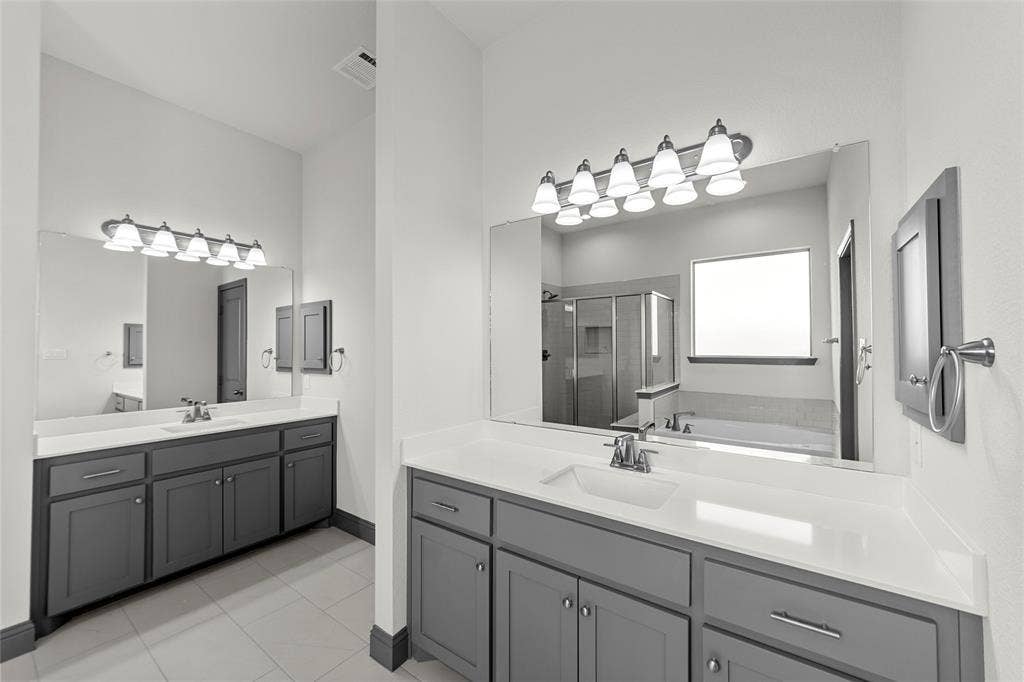 Dual vanities featuring gray cabinetry and white countertops