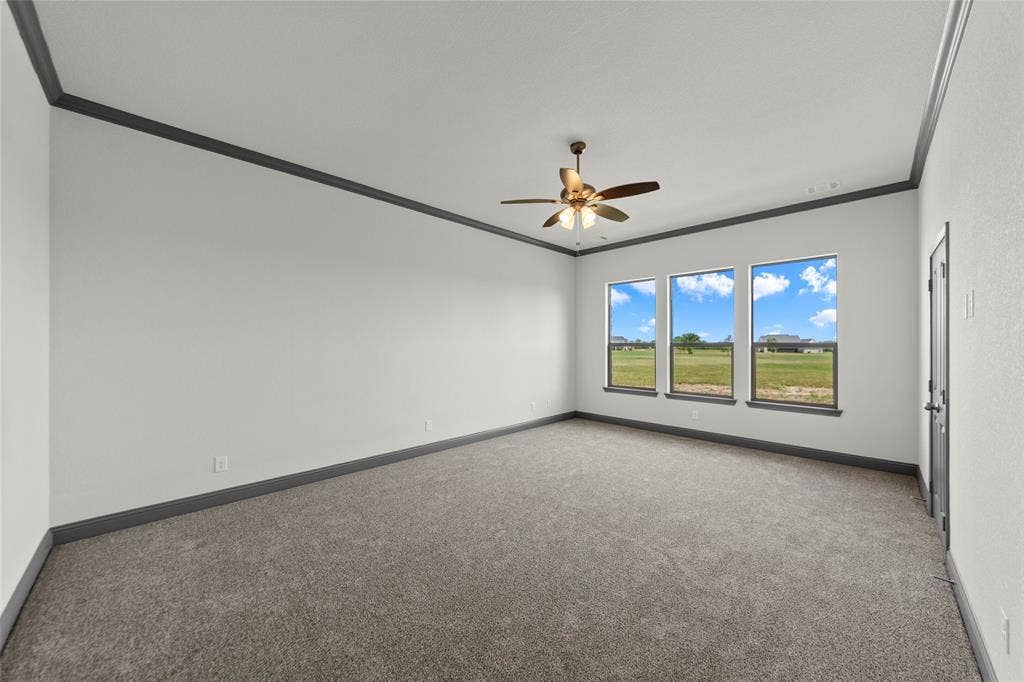Spacious room featuring three large windows, a ceiling fan with integrated lighting, and gray-toned trim