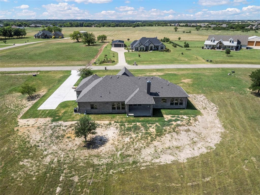 Single-story residence featuring a gray shingle roof, brick exterior, and a concrete driveway