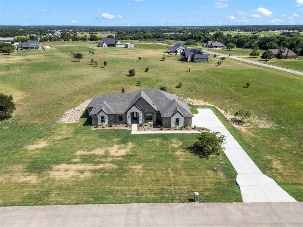 Expansive property featuring a contemporary home with a dark brick and light stone exterior, a concrete driveway, and a large manicured lawn