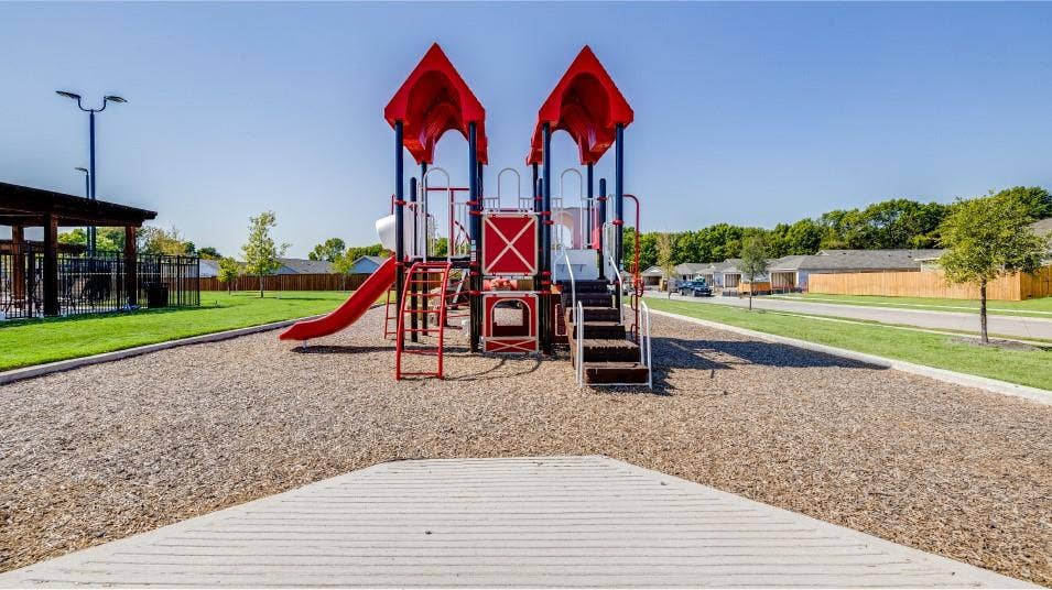 6307 Sandpiper Lane, Princeton, TX 75407 Outdoor play structure with red slides and blue support beams, set on a wood chip surface
