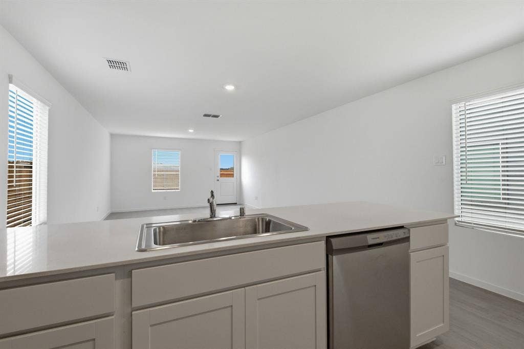 6307 Sandpiper Lane, Princeton, TX 75407 Kitchen island featuring a stainless steel sink, a stainless steel dishwasher, and a light-toned countertop
