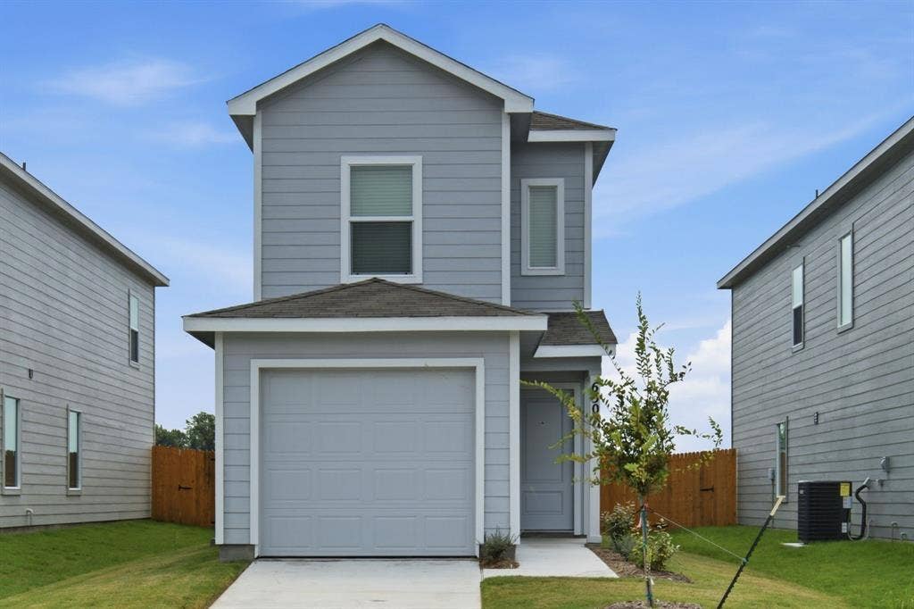 6307 Sandpiper Lane, Princeton, TX 75407 Two-story residence featuring light gray siding with white trim, an attached front-facing garage, and a concrete driveway