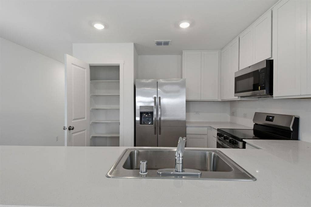 6307 Sandpiper Lane, Princeton, TX 75407 Modern kitchen featuring an undermount stainless steel sink, a stainless steel side-by-side refrigerator, and a stainless steel oven range with an overhead microwave