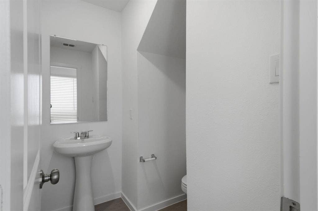 6307 Sandpiper Lane, Princeton, TX 75407 Pedestal sink with chrome faucet and rectangular mirror in a bright powder room