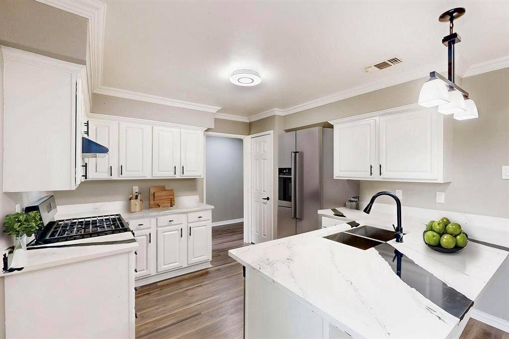 *Virtually staged*  Kitchen featuring a sink, light wood-style floors, white cabinetry, and crown molding