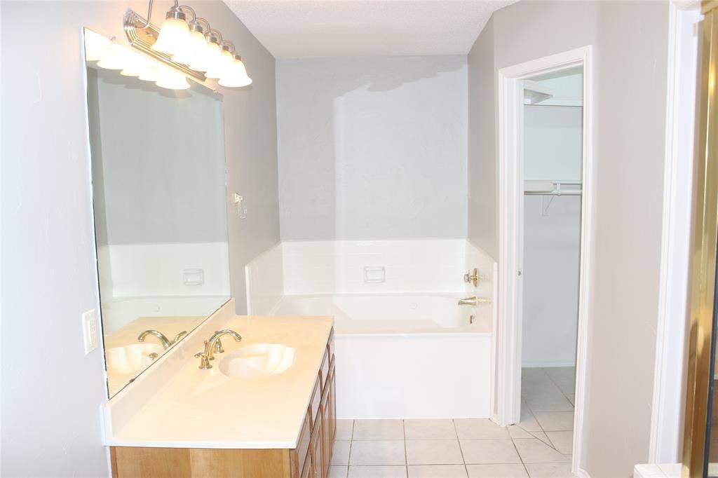 285 Alex Drive, Coppell, TX 75019 Bathroom featuring a single vanity with wood-finish cabinetry, a white countertop, and an undermount sink