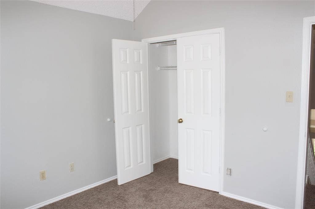 285 Alex Drive, Coppell, TX 75019 Bedroom featuring a vaulted ceiling, light gray wall paint, and plush carpet flooring