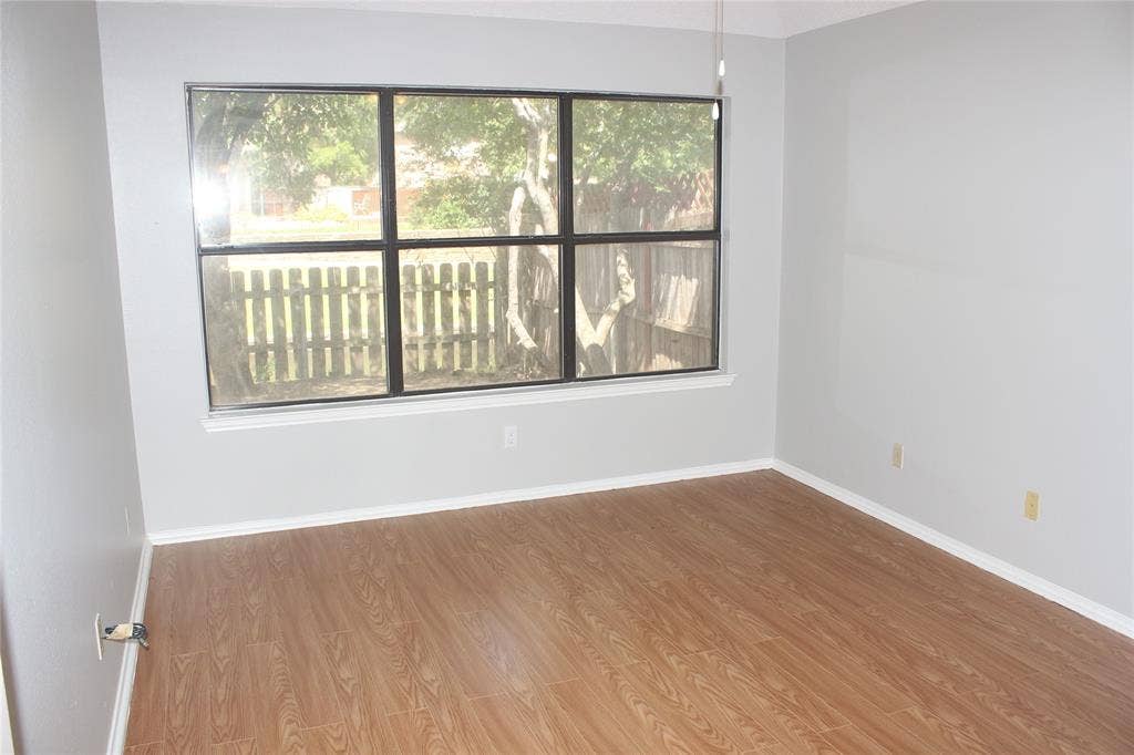 285 Alex Drive, Coppell, TX 75019 Spacious room featuring wood-finish flooring, light gray wall paint, and white baseboards