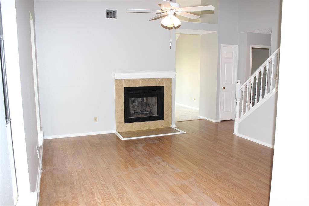 285 Alex Drive, Coppell, TX 75019 Living area featuring wood-finish flooring, a fireplace with a tiled surround and hearth, a ceiling fan, and painted walls