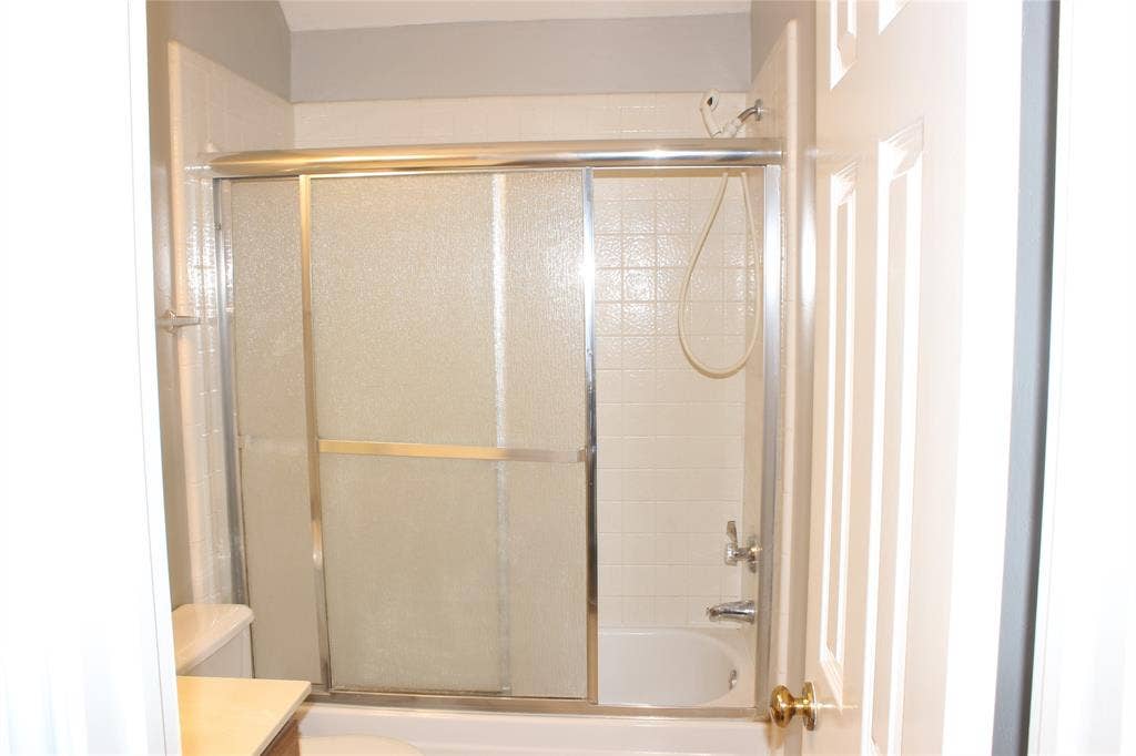 285 Alex Drive, Coppell, TX 75019 Bathroom featuring a tub/shower combination with sliding glass doors and white subway tile surround