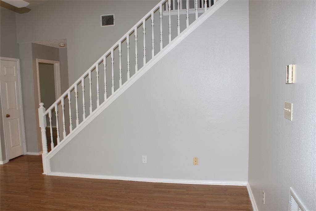285 Alex Drive, Coppell, TX 75019 Staircase featuring white balusters and handrail, gray wall paint, wood-finish flooring, and white baseboards