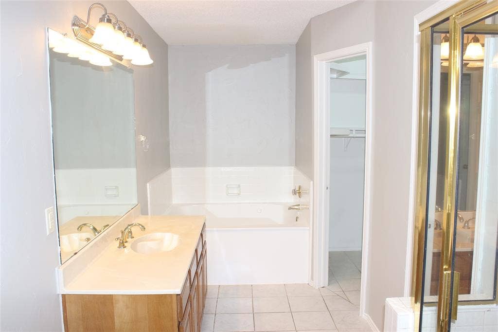 285 Alex Drive, Coppell, TX 75019 Bathroom featuring a single vanity with wood-finish cabinetry, a light-colored countertop, and a large wall mirror