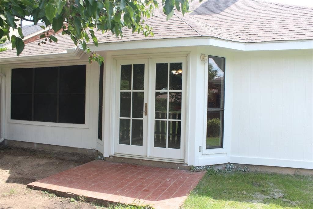 285 Alex Drive, Coppell, TX 75019 Exterior white siding featuring a bay window with a tall, narrow pane, a large window with black screening, and glass French doors