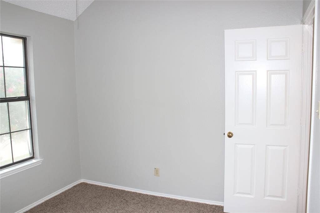 285 Alex Drive, Coppell, TX 75019 Interior room with light gray walls, textured carpet flooring, and a vaulted ceiling