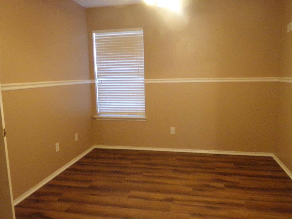 4708 Topaz Lane, Granbury, TX 76049 Room featuring wood-finish flooring, a window with blinds, and neutral-toned walls with decorative trim
