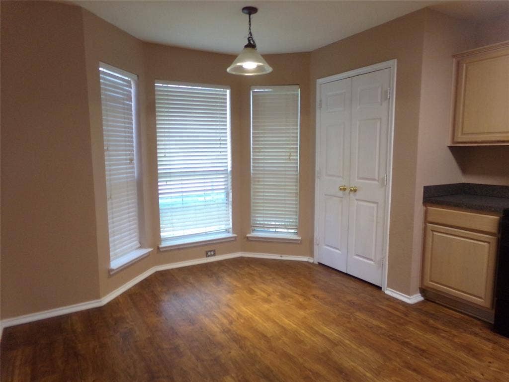 4708 Topaz Lane, Granbury, TX 76049 Bay window dining area featuring wood-finish flooring, a ceiling-mounted light fixture, white blinds, and base molding