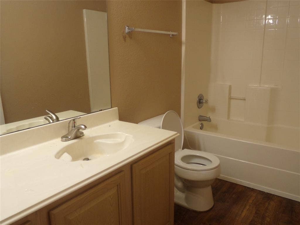 4708 Topaz Lane, Granbury, TX 76049 Hall Bathroom featuring wood-finish flooring, a vanity with a light-colored countertop and integrated sink, chrome-finish faucet, and a shower-tub combination with a white surround