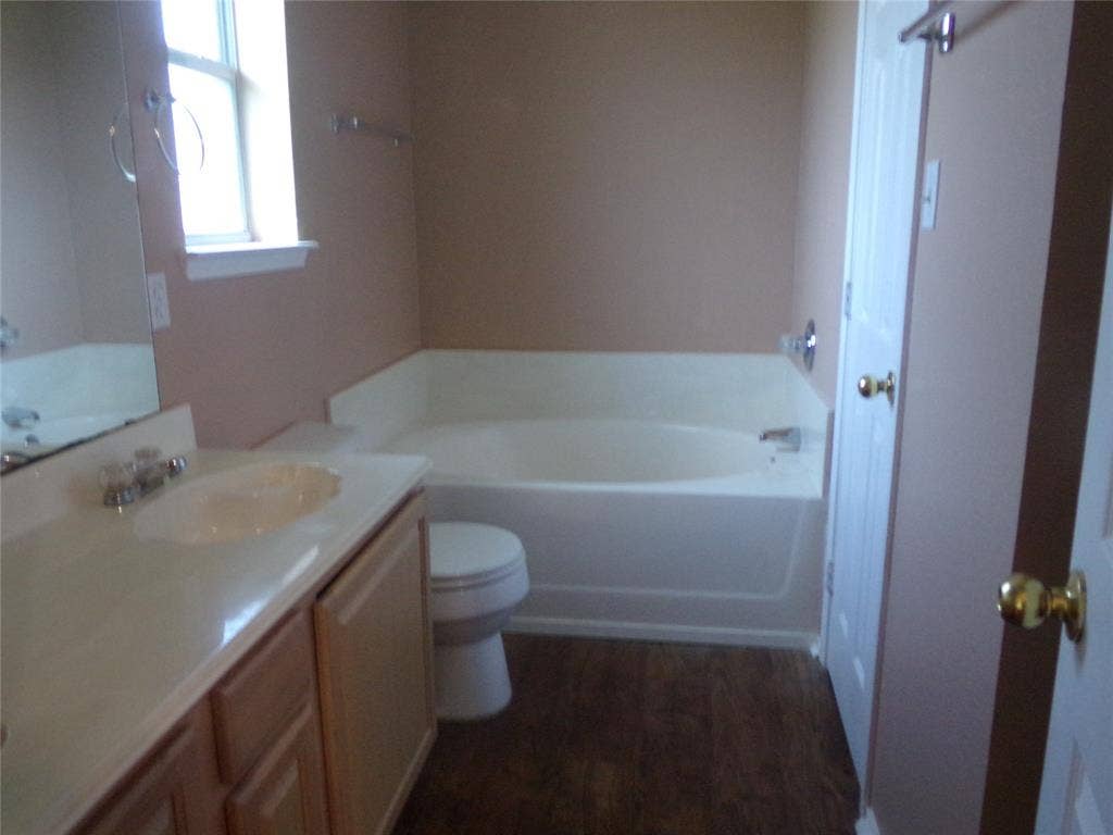 4708 Topaz Lane, Granbury, TX 76049 Bathroom featuring a single vanity with a built-in sink, light wood-finish cabinetry, and a full-size bathtub