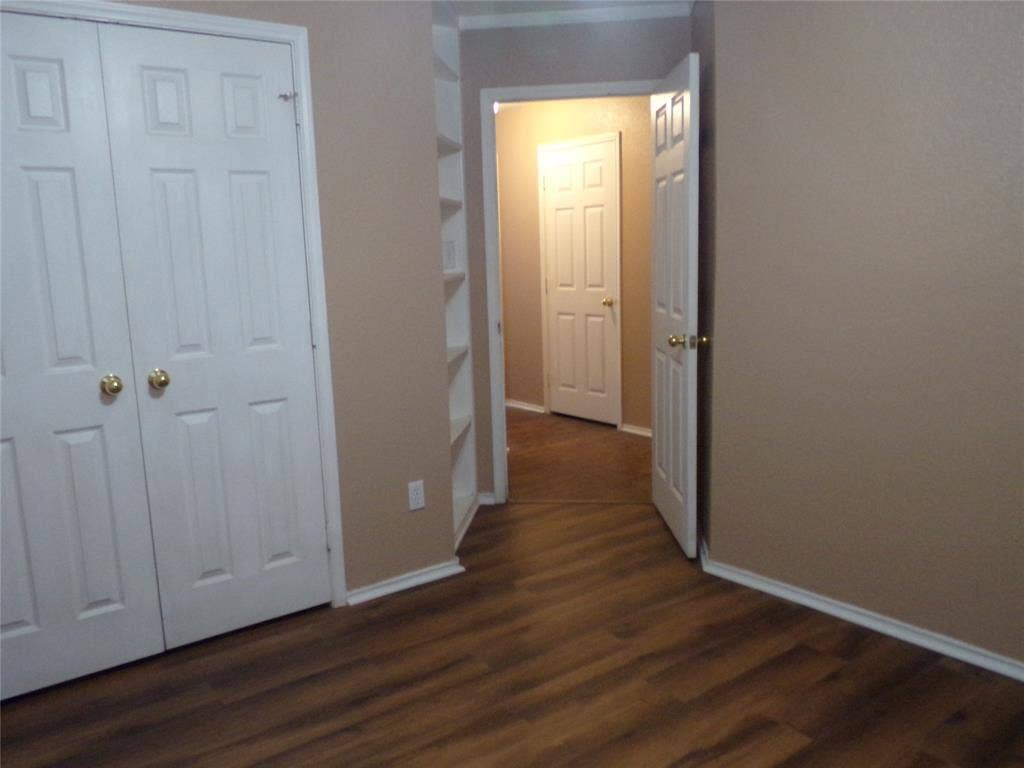 4708 Topaz Lane, Granbury, TX 76049 Wood-finish flooring throughout, featuring a double-door closet with gold-toned hardware, white baseboards, and built-in shelving