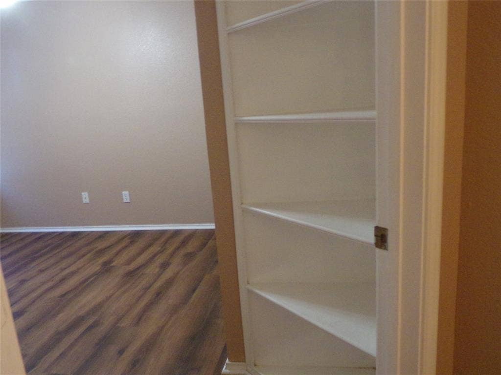 4708 Topaz Lane, Granbury, TX 76049 Built-in shelving unit with multiple white shelves, set against a neutral painted wall and wood-finish flooring