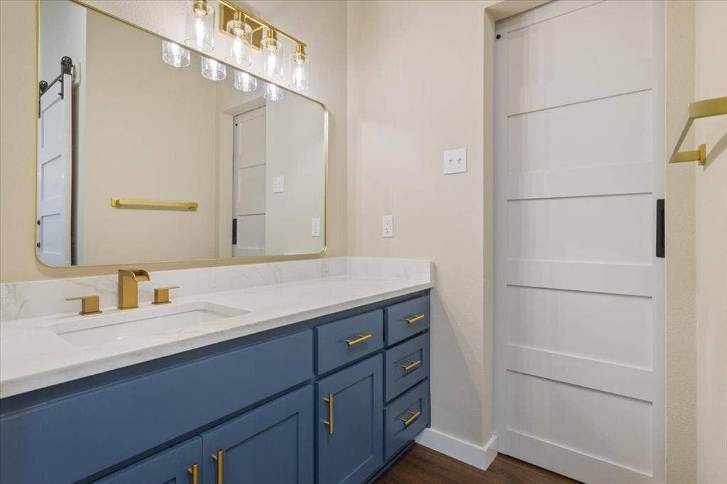 116 Boleman Drive, Hewitt, TX 76643 Bathroom vanity featuring a white countertop with an undermount sink, brass finish hardware, a matching brass faucet, and a large framed mirror