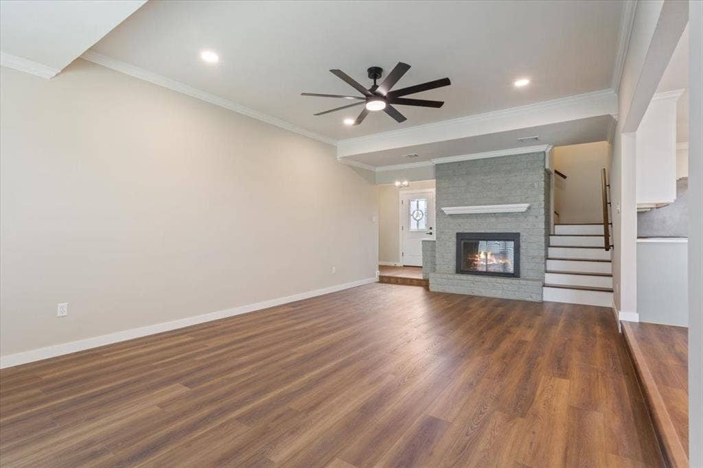 116 Boleman Drive, Hewitt, TX 76643 Spacious living area featuring a wood burning fireplace with glass doors, remote controlled ceiling fan, LVP wood-finish flooring, recessed lighting, and crown molding