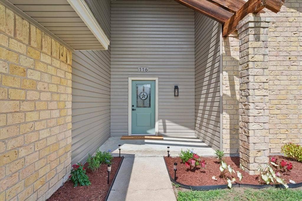 116 Boleman Drive, Hewitt, TX 76643 Inviting entryway featuring a light blue door with decorative glass, enhanced by fresh mulch and landscaping