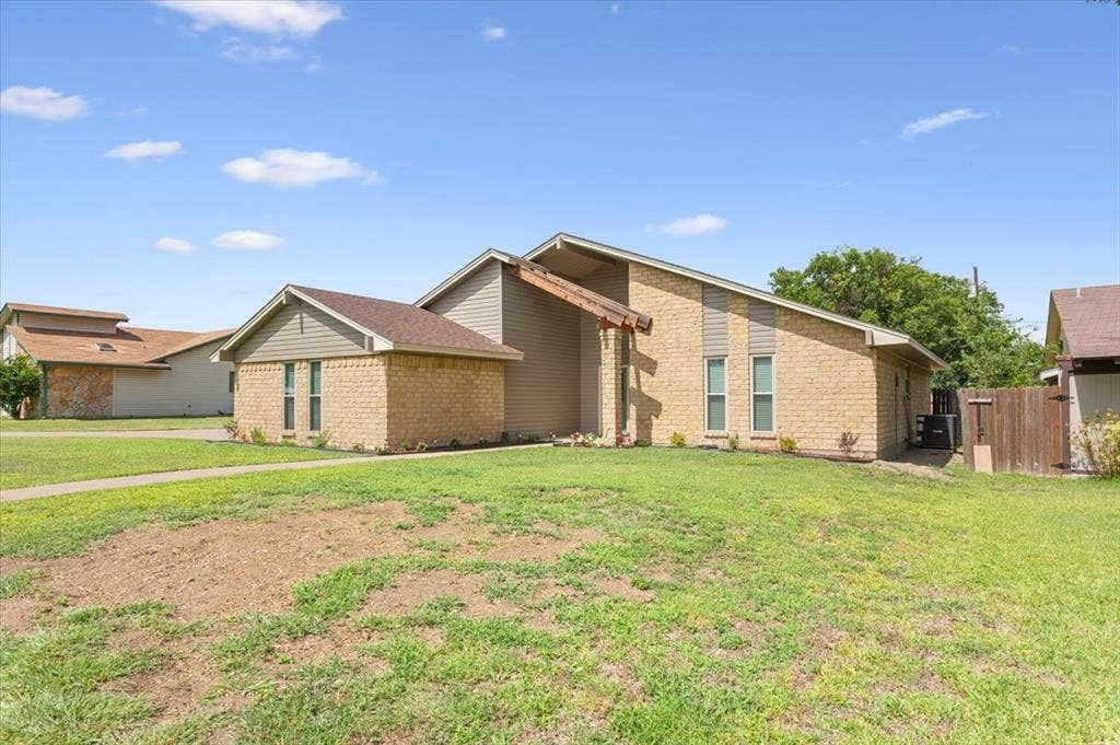 116 Boleman Drive, Hewitt, TX 76643 Side view of home featuring light-colored brick veneer, large stained beams over entry way, and fresh landscaping