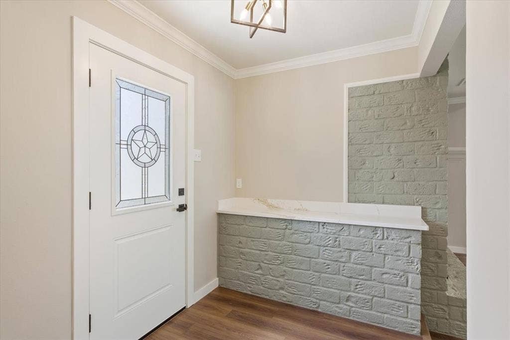 116 Boleman Drive, Hewitt, TX 76643 Entryway featuring a decorative glass panel front door, crown molding, wood-finish LVP flooring, and a brick-look half-wall with a light-colored quartz countertop
