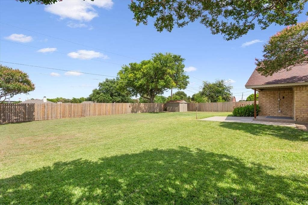 116 Boleman Drive, Hewitt, TX 76643 Expansive backyard featuring a large grass lawn, wood privacy fencing, a concrete patio, and a storage shed