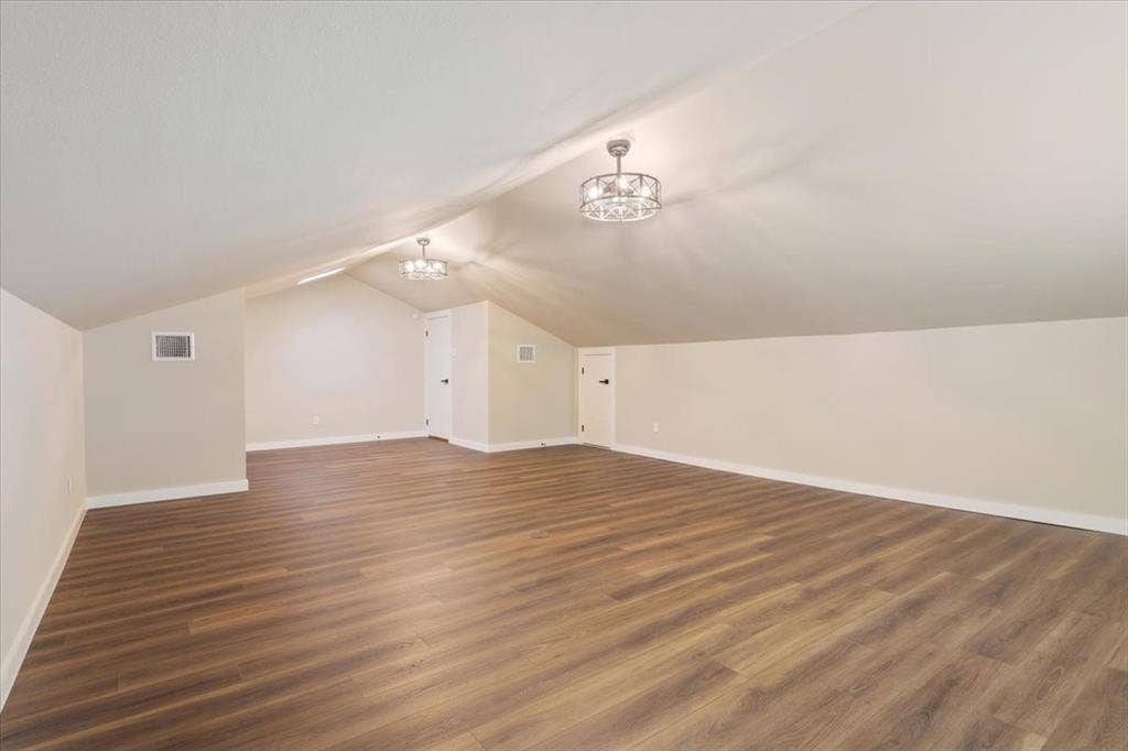 116 Boleman Drive, Hewitt, TX 76643 Spacious 4th bedroom / bonus room featuring LVP wood-finish flooring, a vaulted ceiling, a built-in window, two ceiling-mounted decorative light fixtures with ceiling fans (mini), and attic access