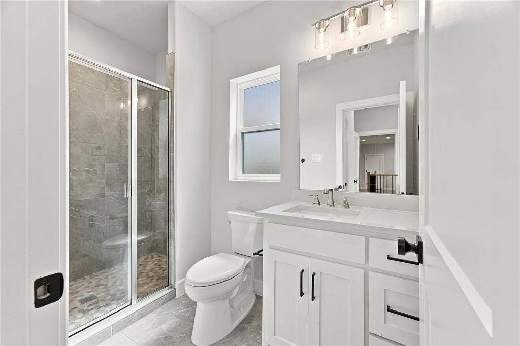 3820 Jacks Loop, Midlothian, TX 76065 Shower with glass enclosure, white vanity with integrated sink, rectangular mirror, and window