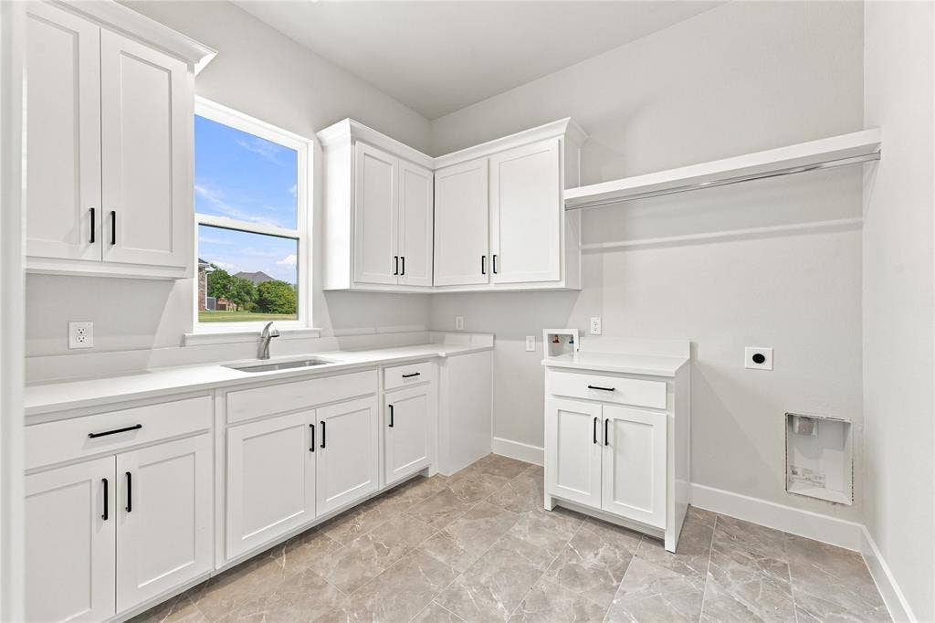 3820 Jacks Loop, Midlothian, TX 76065 White shaker-style cabinetry with black hardware, light-toned countertops, a stainless steel sink with a gooseneck faucet, a window, and a built-in hanging rod