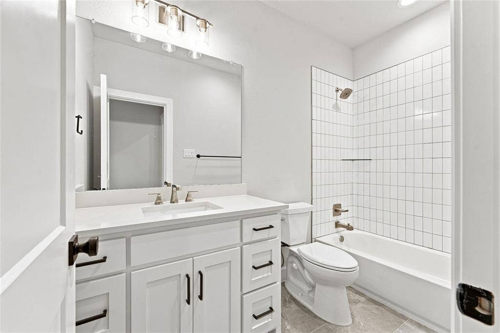 3820 Jacks Loop, Midlothian, TX 76065 White vanity with integrated sink and brushed nickel faucet, large mirror, vertical subway tile shower surround, and grey tile flooring