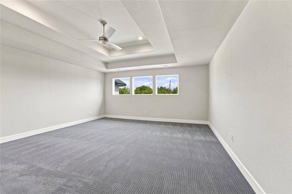 3820 Jacks Loop, Midlothian, TX 76065 Spacious room featuring a tray ceiling with recessed lighting, a ceiling fan, plush gray carpeting, and multiple windows