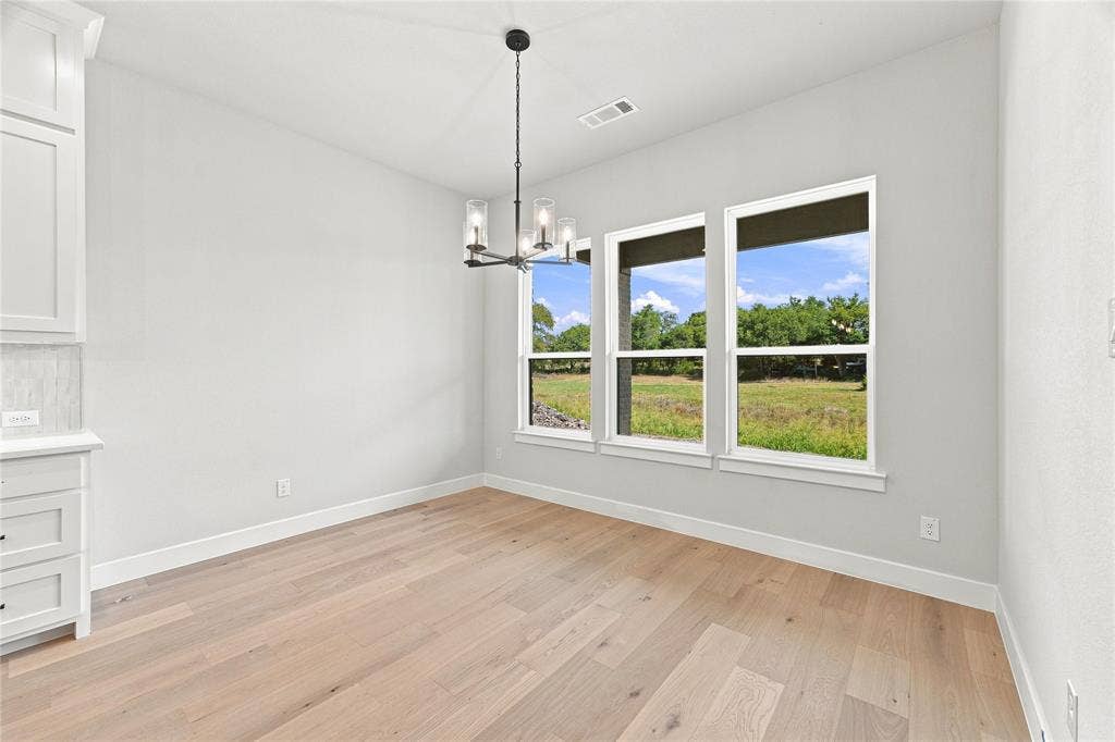 3820 Jacks Loop, Midlothian, TX 76065 Wood-finish flooring, three large windows, a modern chandelier with clear glass shades, and white built-in cabinetry