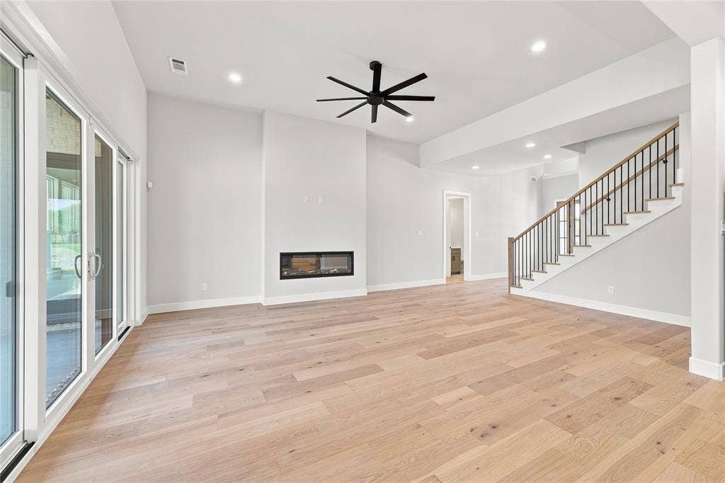 3820 Jacks Loop, Midlothian, TX 76065 Wood-finish flooring, built-in fireplace, sliding glass doors, recessed lighting, and a staircase with wood handrails and black balusters