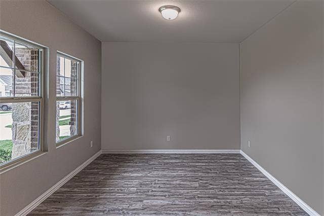 448 Ella Lane, Fate, TX 75087 Interior room with two windows, wood-finish flooring, neutral gray wall paint, white trim, and a flush-mount ceiling light fixture