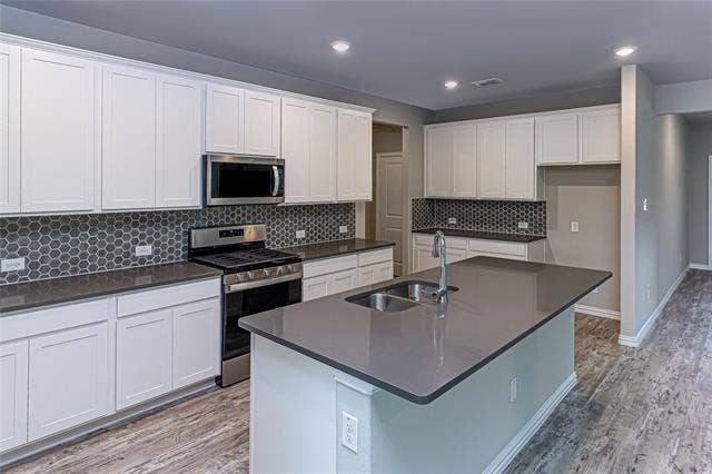 448 Ella Lane, Fate, TX 75087 Modern kitchen featuring a central island with an undermount double sink, gray countertop, and contemporary faucet